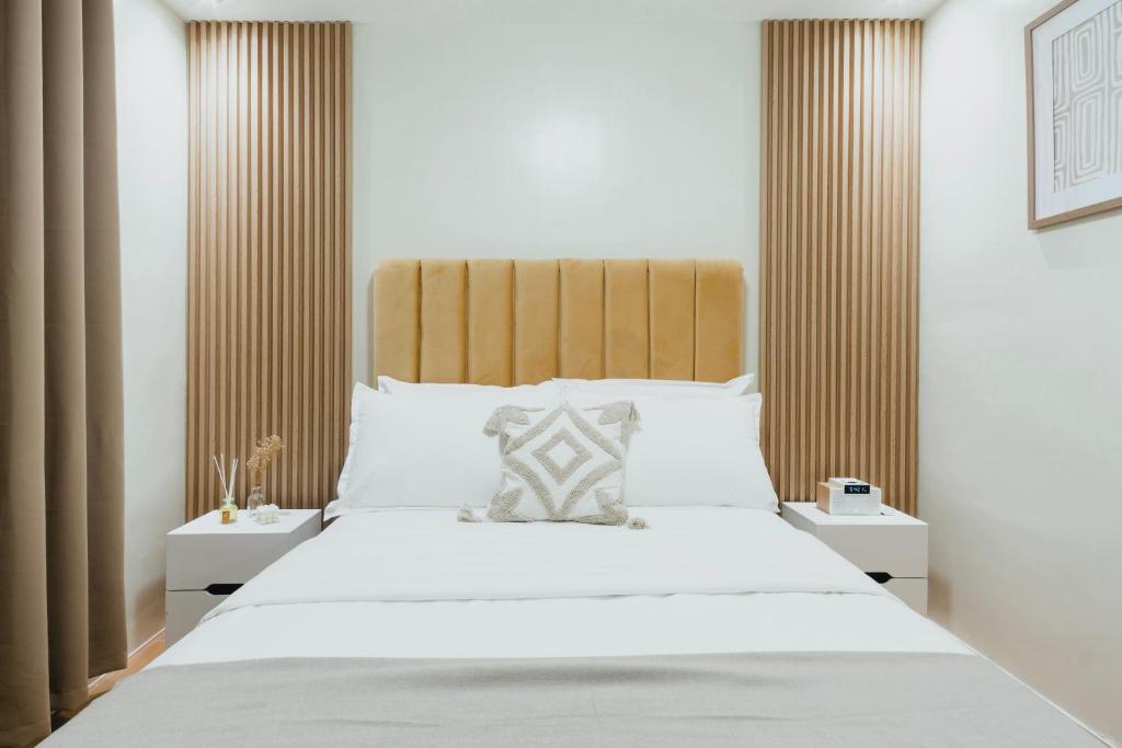 um quarto com uma grande cama branca e uma cabeceira em madeira em The Constant Cove – 3BR Condo Near Airport, Samal Island & Malls em Davao
