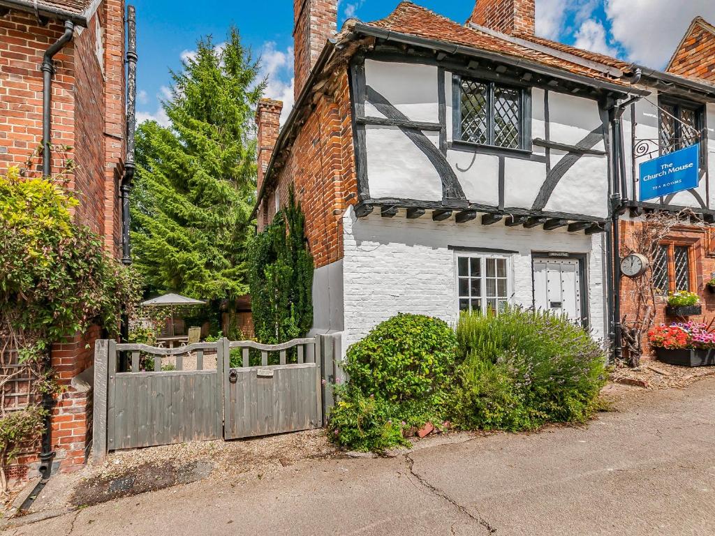 a white and black house with a wooden gate at Orions Cottage in Chilham