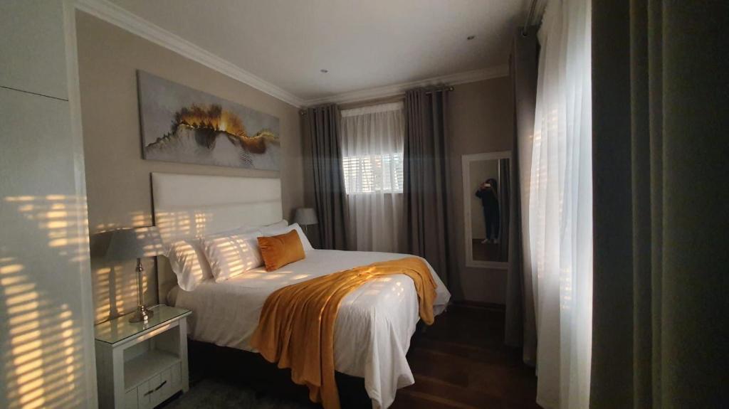 a bedroom with a bed with an orange blanket at Home Away from Home - Deluxe Queen & Twin Apartment in Johannesburg