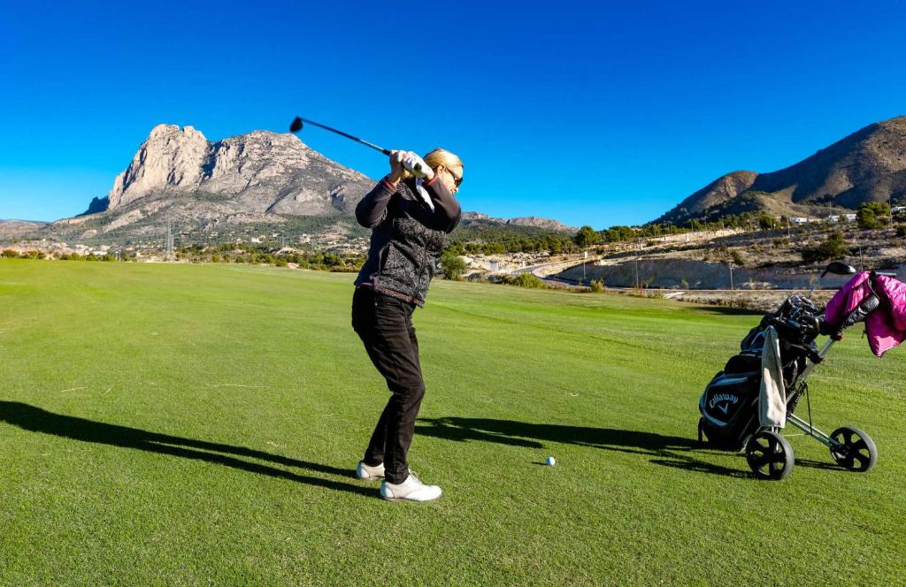 Un uomo che dondola una mazza da golf su un campo da golf di Apartamento Alcotan IF Beach a Cala de Finestrat