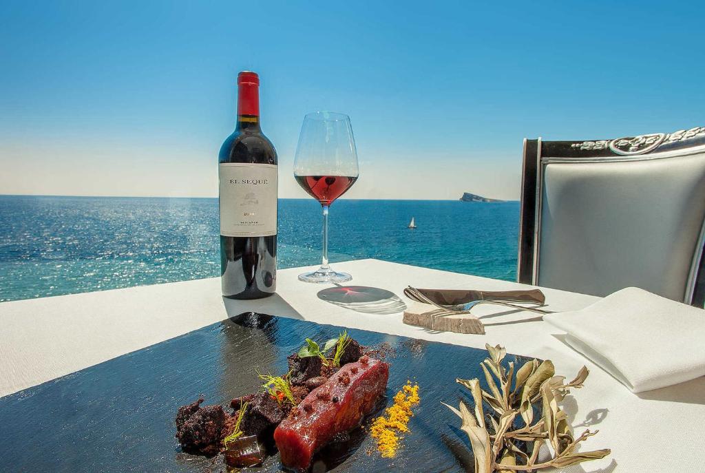 a table with a glass of wine and a plate of food at Apartamento Cruzamar IF Beach in Benidorm