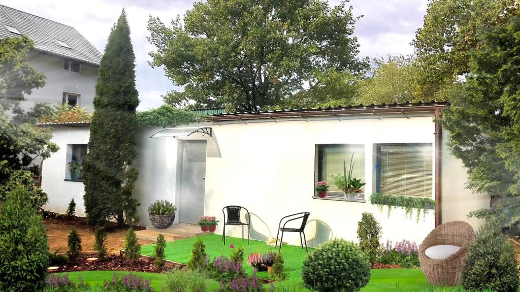 a white house with a garden in front of it at Pokoje pod Dębem in Józefów