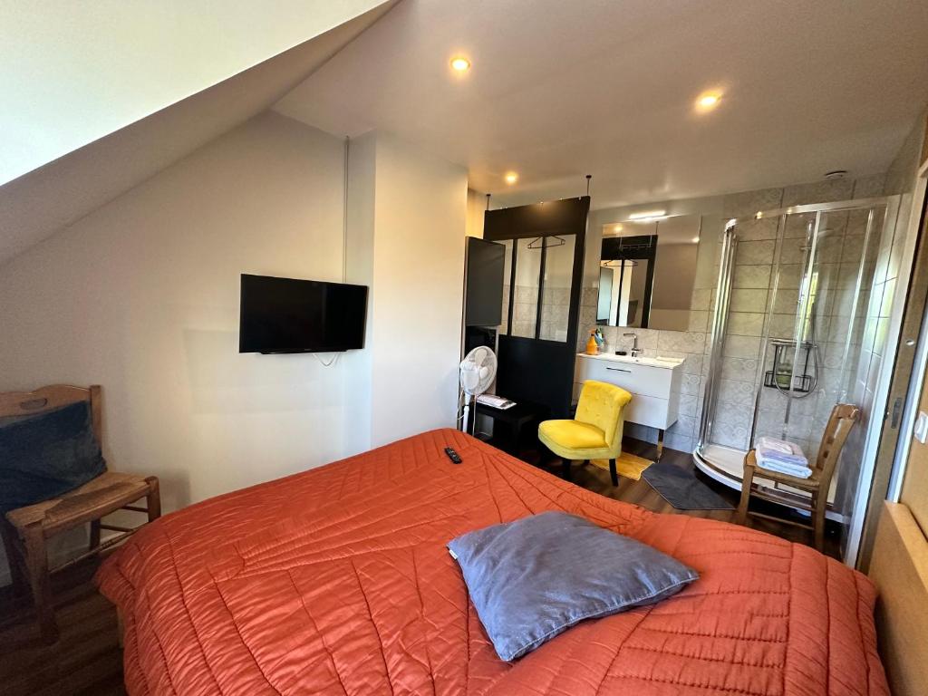 a bedroom with an orange bed and a bathroom at Chambre chez Alain et Armelle in Avoine