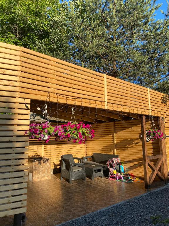 a wooden building with a patio with chairs and flowers at Guest house Shulc in Mizhhirya