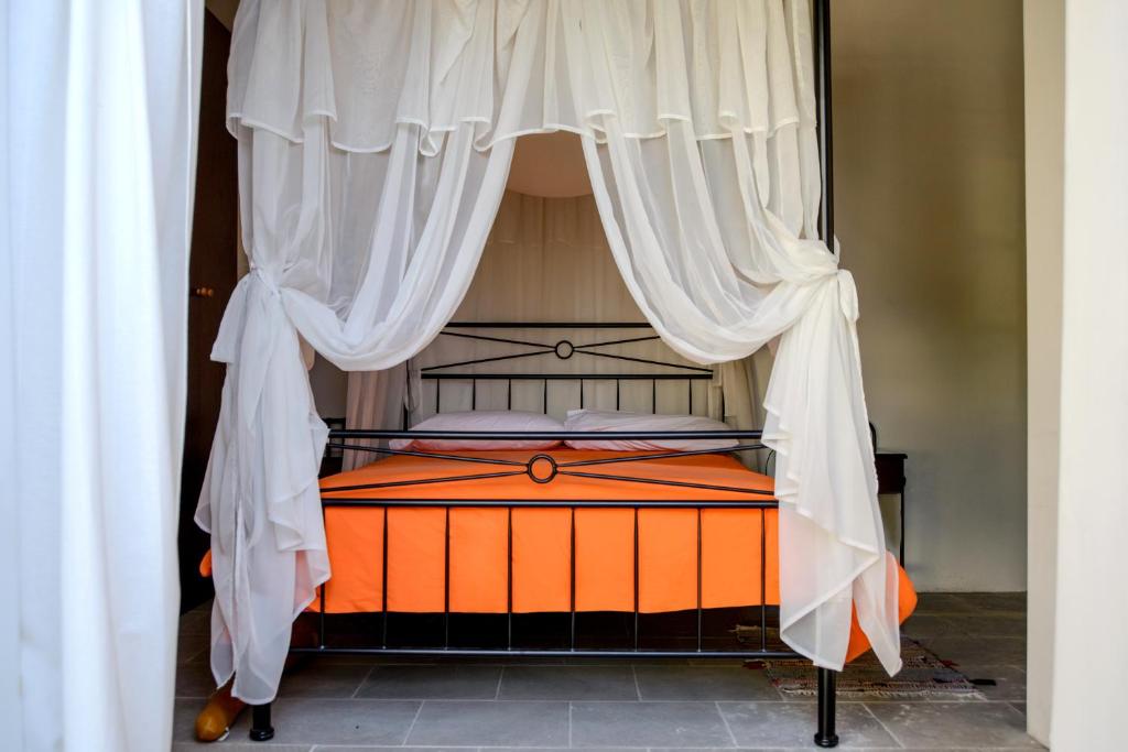an orange bed with white curtains in a bedroom at Kozakos Luxury House in Pano Lefkara