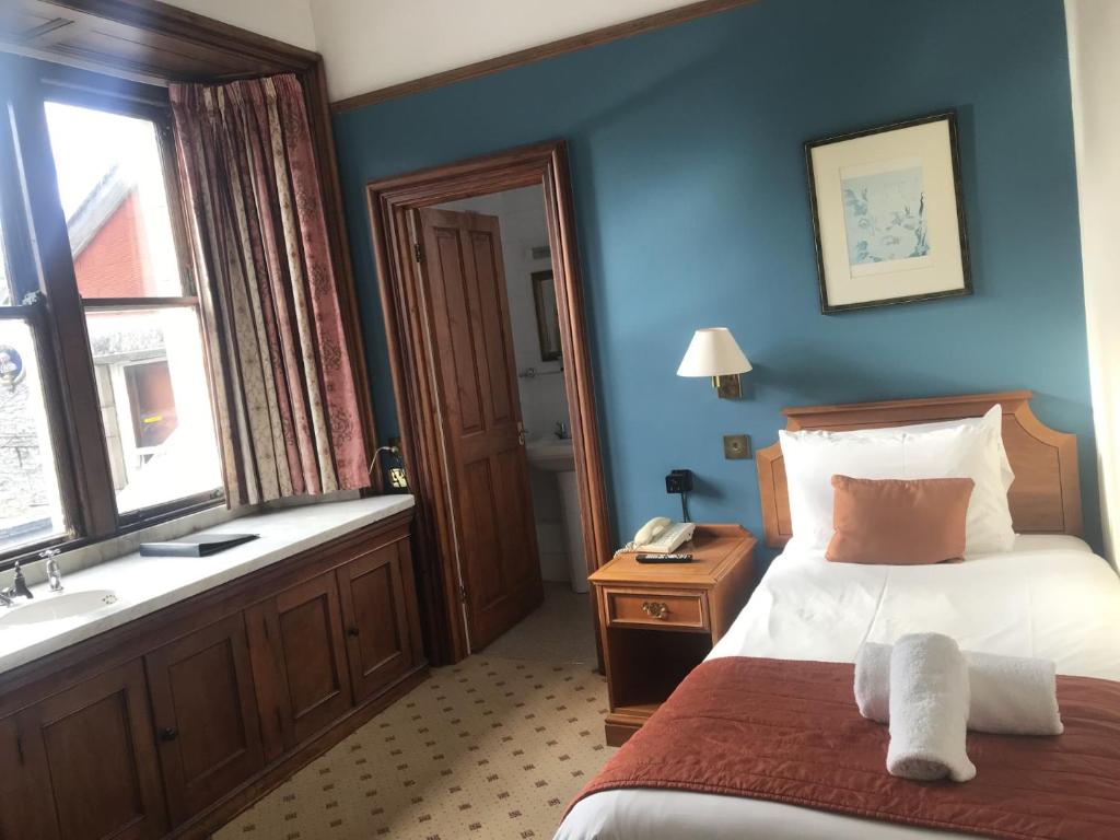 a bedroom with a bed and a bathroom with a sink at Purbeck House Hotel & Louisa Lodge in Swanage