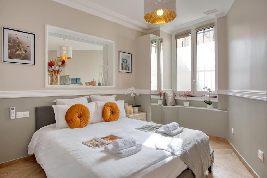 une chambre avec un grand lit blanc avec des oreillers orange dans l'établissement Charming Apart NEW 2 Bedrooms with Aircon, à Paris