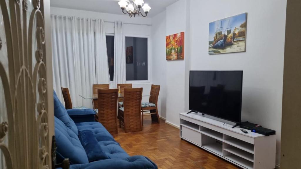 uma sala de estar com um sofá azul e uma televisão em Apartamento 3 quartos em Copacabana no Rio de Janeiro
