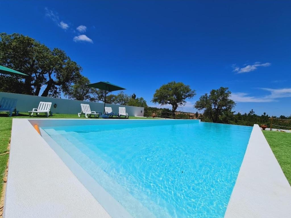 a large swimming pool with blue water in a yard at Monte Argil in Montargil