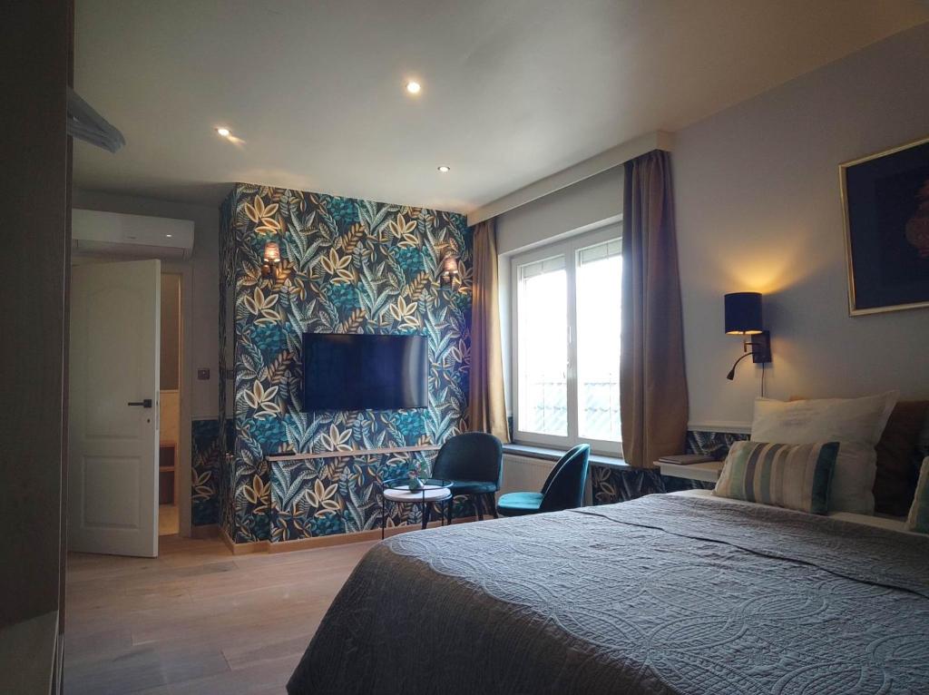 een hotelkamer met een bed en een tv aan de muur bij Boutique hotel Het Bloemenhof in Dudzele