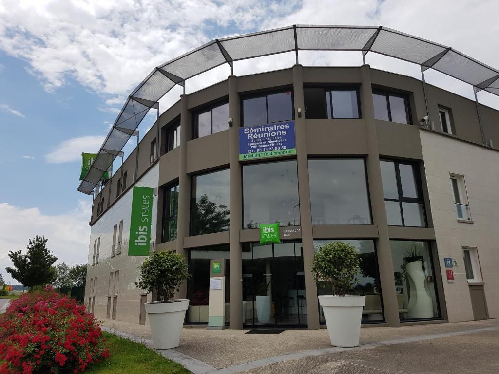 a building with two potted plants in front of it at ibis Styles Compiegne in Jaux