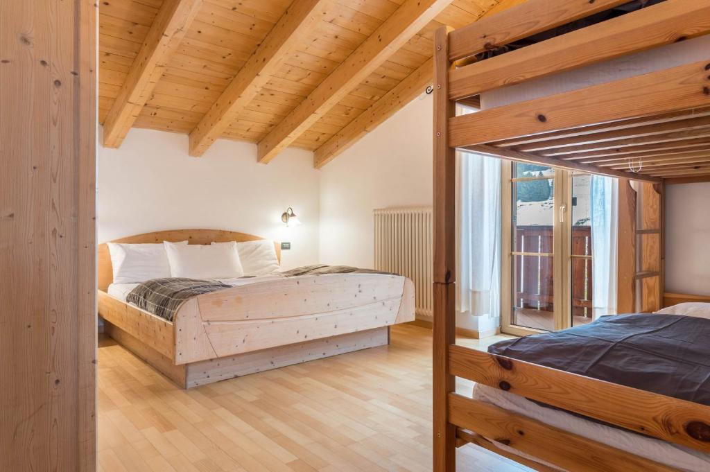 a bedroom with two beds and a wooden ceiling at Casa Titol Ami in Pozza di Fassa