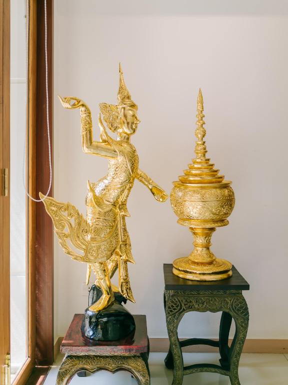 a gold statue of a woman on a table next to a vase at Rendezvous Classic House in Chiang Mai