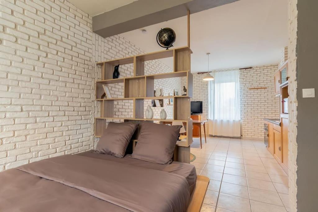 a bedroom with a bed and a brick wall at Le Graphite in Auboué