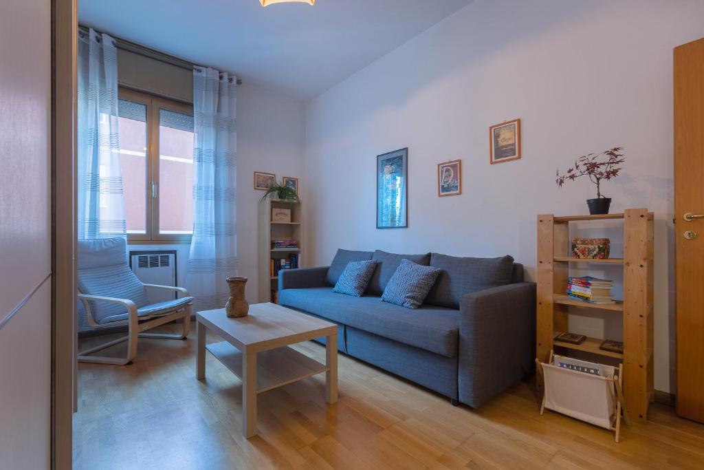 ein Wohnzimmer mit einem blauen Sofa und einem Tisch in der Unterkunft Bologna City Retreat a due passi dalla Fiera in Bologna