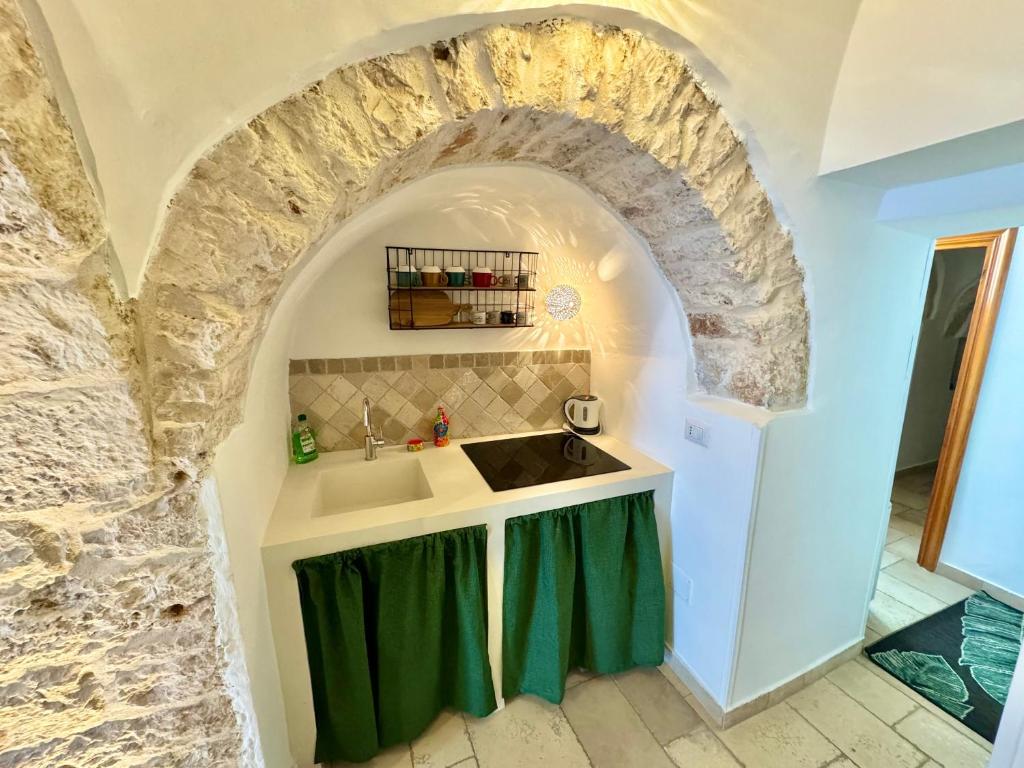 - une cuisine avec un évier et un mur en pierre dans l'établissement Trulli Fenice Alberobello, à Alberobello