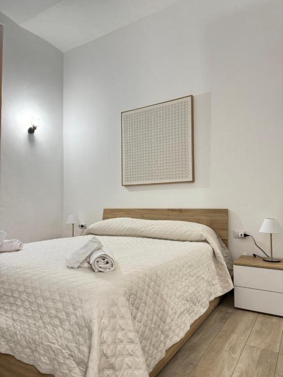 - une chambre blanche avec un lit et une photo sur le mur dans l'établissement Appartamento Colomba, à Plaisance