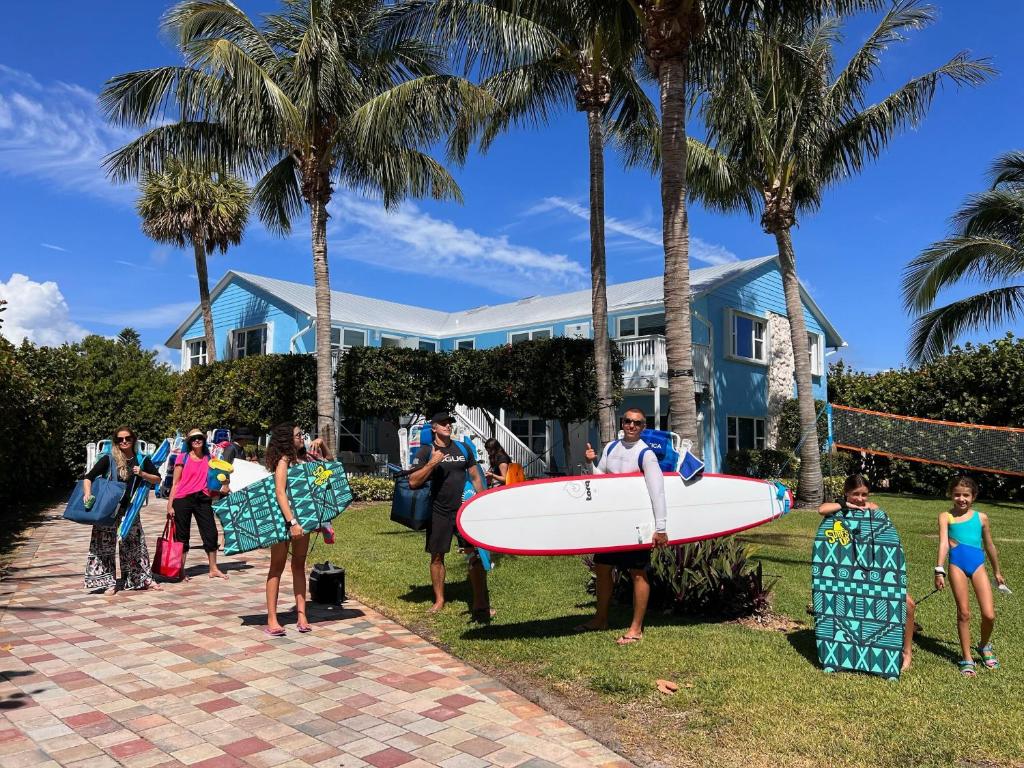 a group of people holding a surfboard in front of a house at Steps to Private Beach - Sand, Surf, Sun - 2bd,2ba in Fort Pierce
