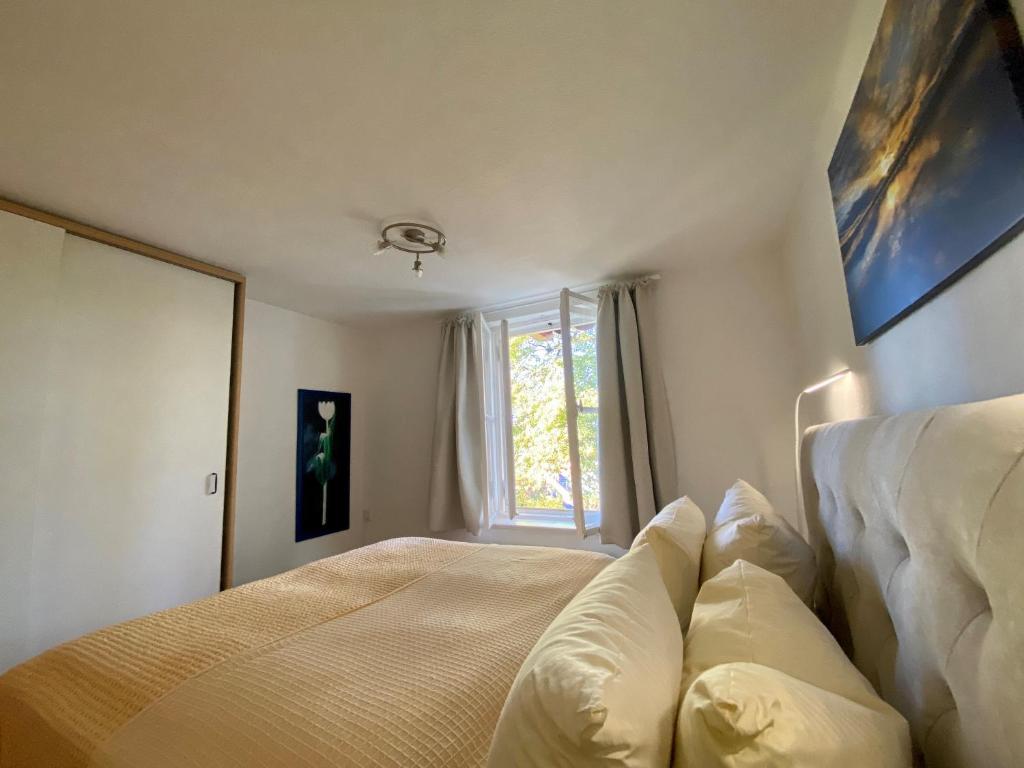 1 dormitorio con cama con almohadas y ventana en Ferienwohnung Prinzenhöhe, en Herrsching am Ammersee