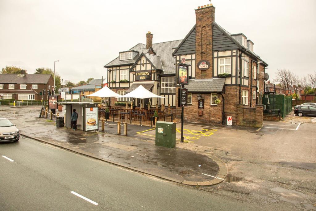 an old building with tables and umbrellas on a street at Fairway Inn in Manchester