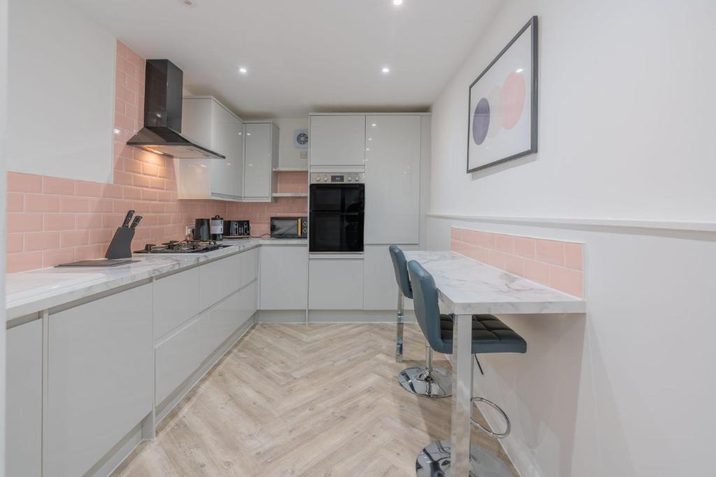 a kitchen with white cabinets and a table with chairs at Four Bed House At Primal Estates Short Lets in Brighton in Brighton & Hove