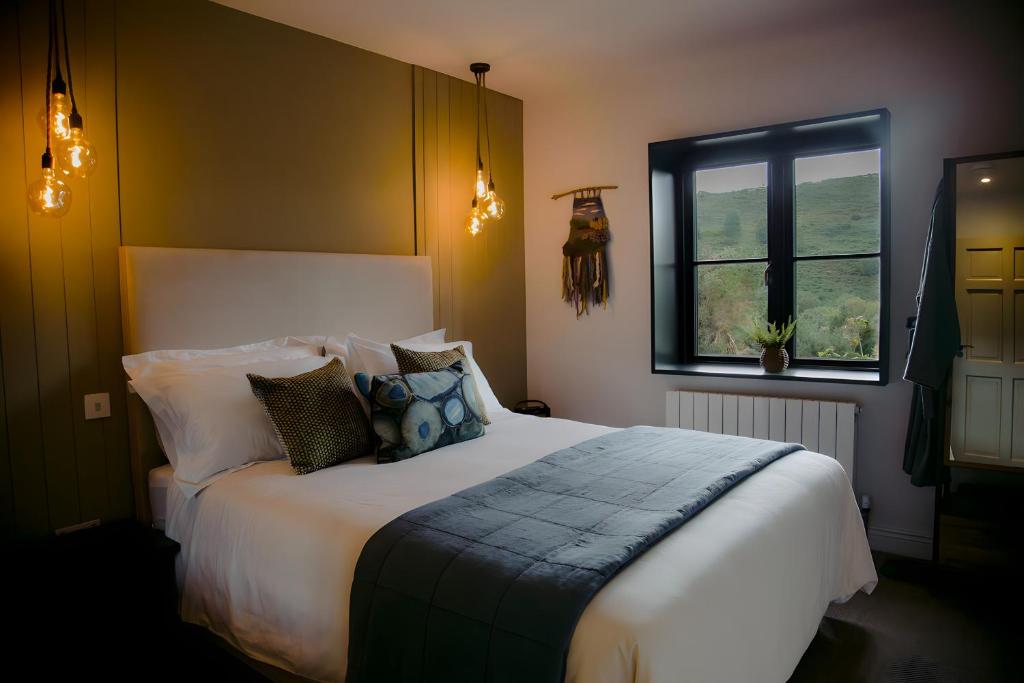1 dormitorio con cama con almohadas y ventana en The Deerstone Luxury Eco Hideaway, en Laragh