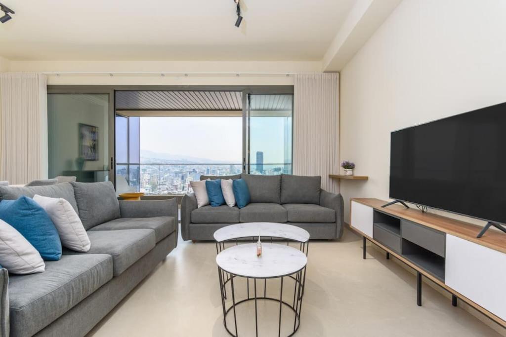 ein Wohnzimmer mit einem Sofa und einem Flachbild-TV in der Unterkunft Denim 3 Bedroom Apartment With Pool in Beirut