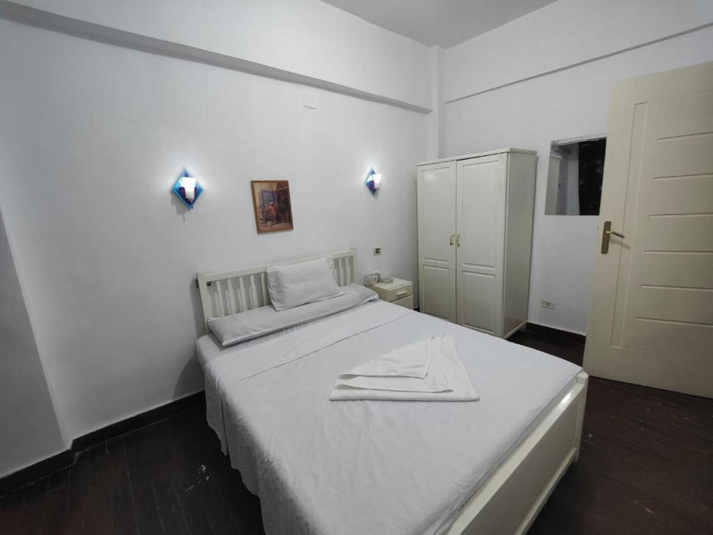 um quarto branco com uma cama com uma toalha em happy home em Luxor