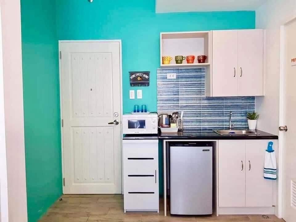 a kitchen with white cabinets and a blue wall at Slice of Paradise La Bella Residences in Tagaytay