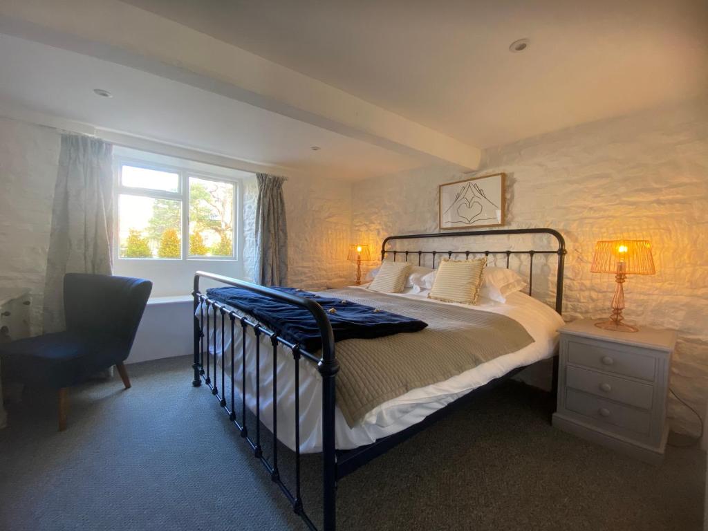 a bedroom with a bed and a chair and a window at The Croft Apartment in Bourton on the Water