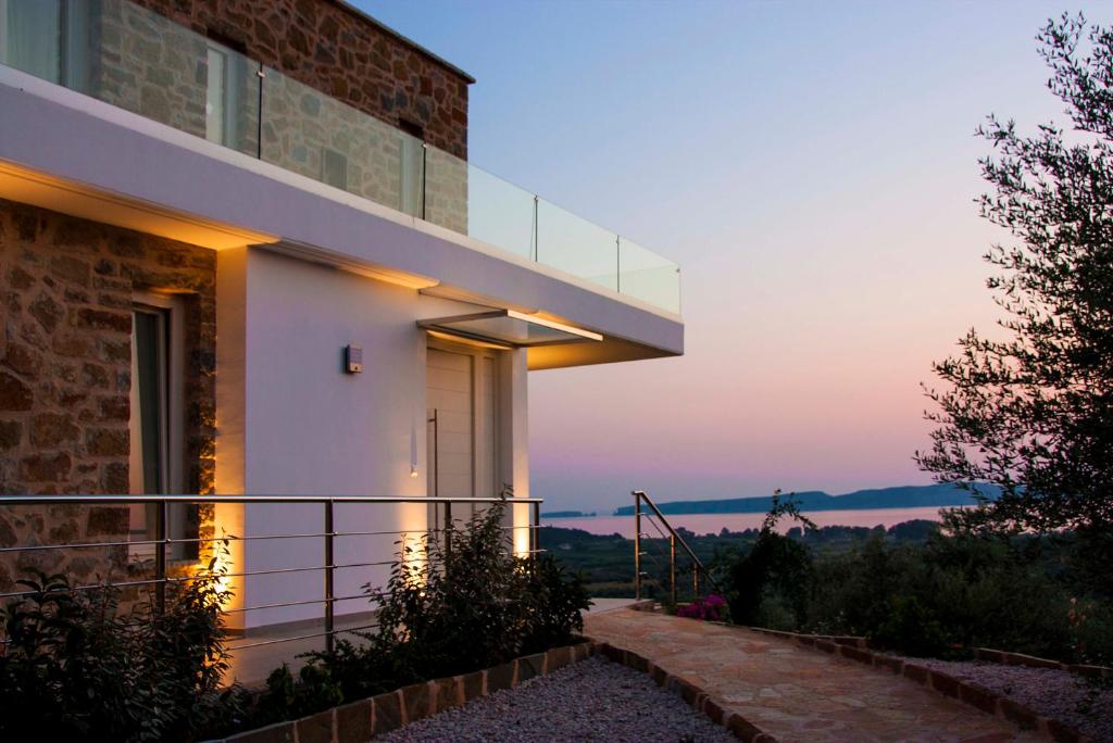 Casa con balcón con vistas a la puesta de sol en el fondo en White Pearl Golf Villa, en Gialova