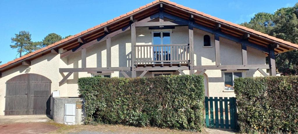 une maison blanche avec un balcon et une clôture dans l'établissement Villa grands pins et spa, à Soustons