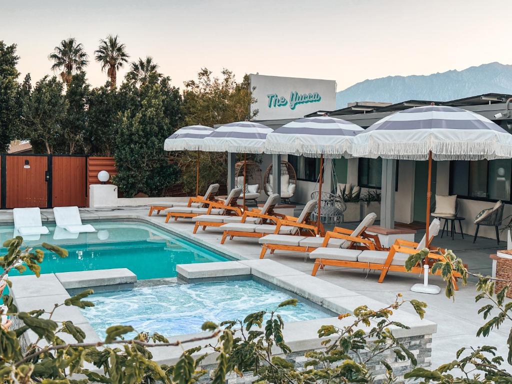 a swimming pool with lounge chairs and umbrellas at The Yucca Hotel in Desert Hot Springs