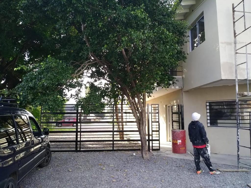 una persona parada frente a un edificio con un árbol en Departamento en Loma Hermosa cercano a Palomar en Loma Hermosa