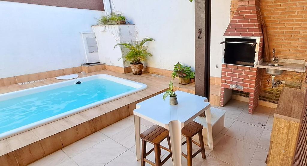 a hot tub in a patio with a table and a table sidx sidx at Linda Casa com Piscina - Praia do Pernambuco - Guarujá in Guarujá