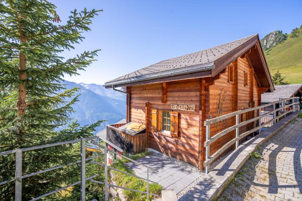 a log cabin in the mountains with a tree at Chalet Collini in Riederalp