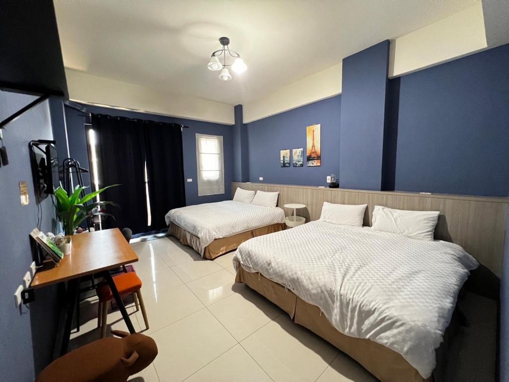 東港的住宿－好客行館，一间卧室设有两张床和蓝色的墙壁