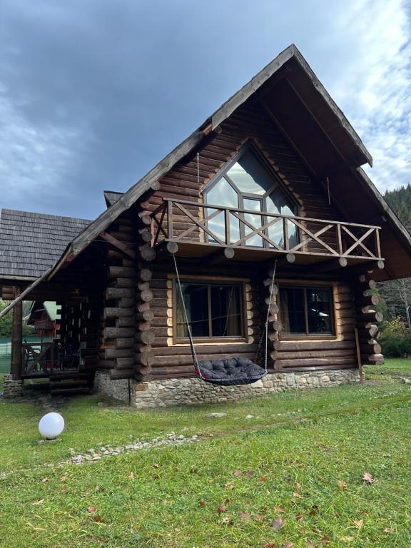 a log cabin with a large window on the side of it at Guest House in Synevyrsʼka Polyana