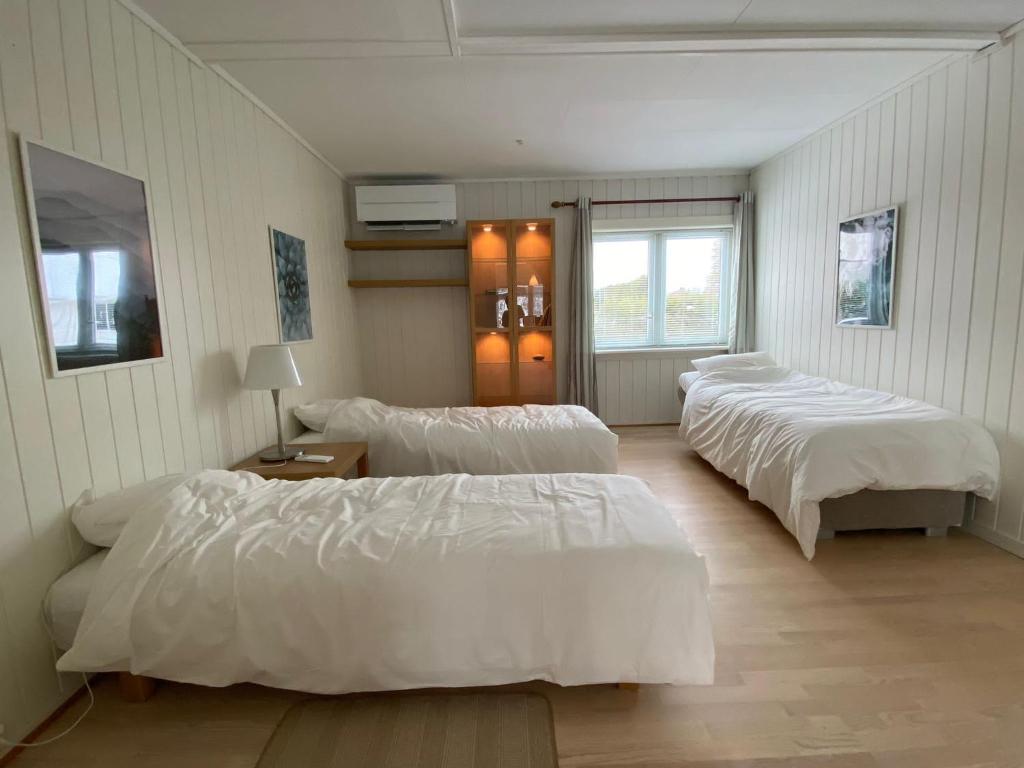 Habitación con 4 camas, sábanas blancas y ventana. en Gardermoen House en Gardermoen