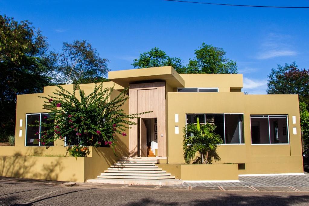 uma casa amarela com uma árvore em frente em Lagos del Peñon, Casa Arena em Girardot