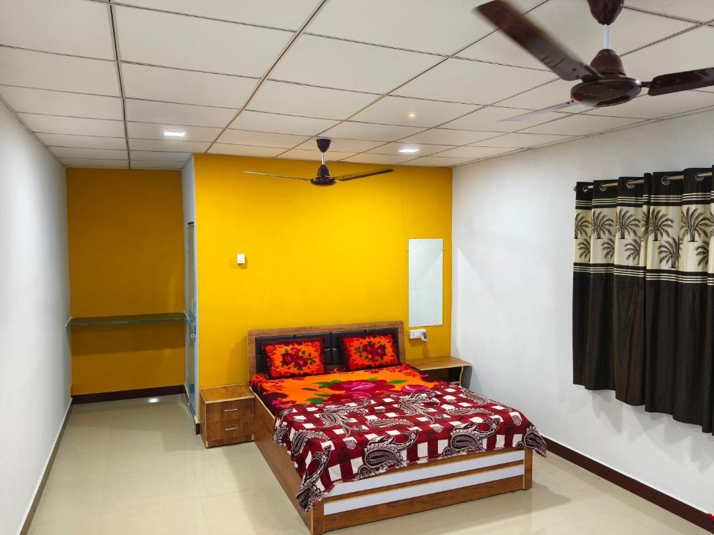 a bedroom with a bed with a yellow wall at Madhav Farmhouse in Sasan Gir