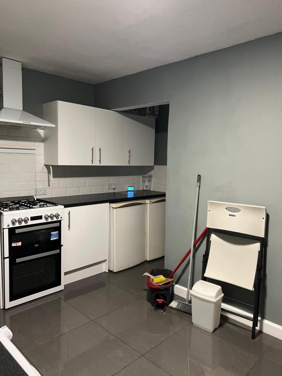 a kitchen with white cabinets and a mop at Oxborne Rooms UK - Seaton in London