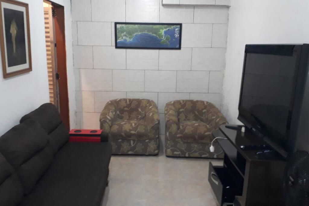 sala de estar con sofá y TV de pantalla plana en Casa a 5 minutos a pé da Praia da Enseada! en Bertioga