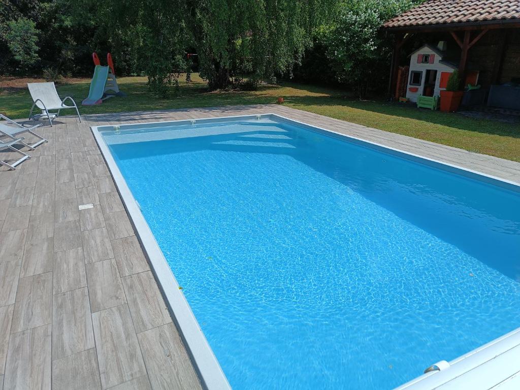 a swimming pool with blue water in a yard at MagHouse in Cestas