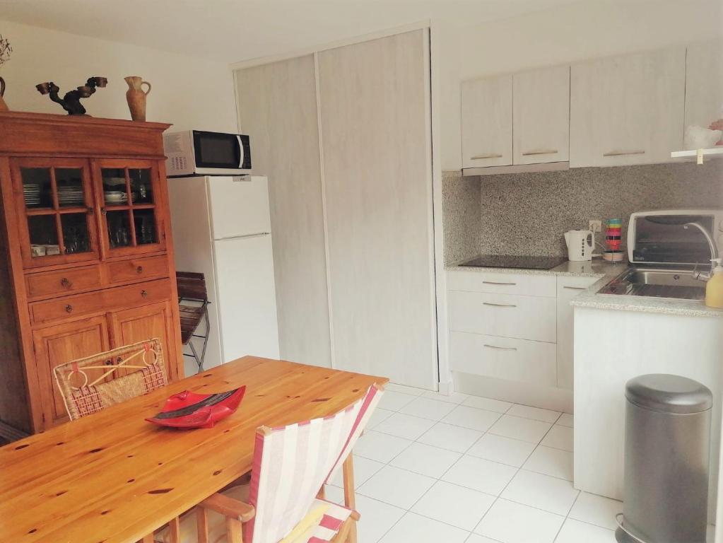 a kitchen with a wooden table and white cabinets at 4SAP22 Appartement climatisé avec double terrasses in Collioure