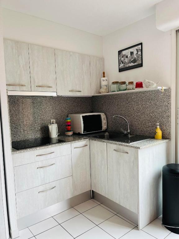 a kitchen with white cabinets and a microwave at 4SAP22 Appartement climatisé avec double terrasses in Collioure