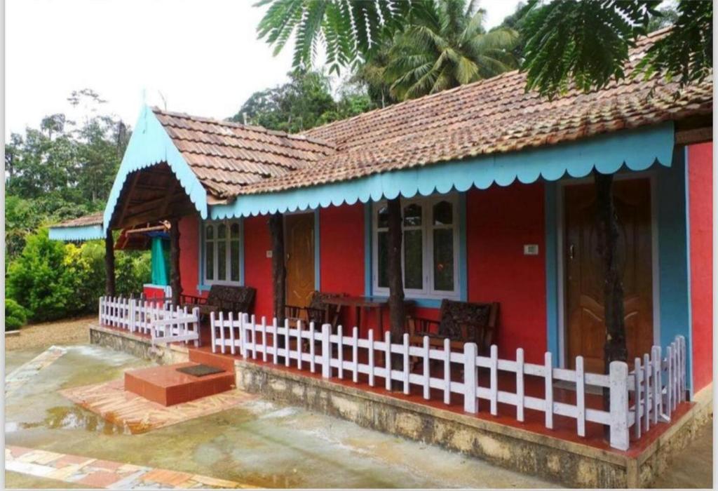 a red house with a white fence in front of it at Hiddenvalley Stays - Nethra in Madikeri