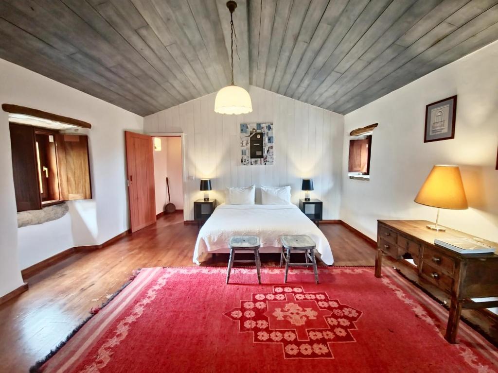 a bedroom with a large bed and a red rug at Villa Pedra Natural Houses in Alvorge