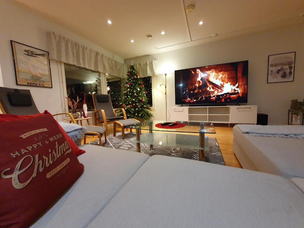 a living room with a fireplace and a christmas tree at Nord Riverside in Rovaniemi