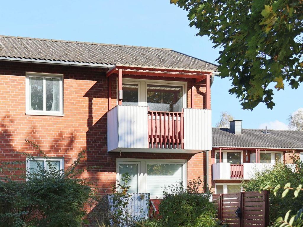 ein rotes Backsteinhaus mit einem weißen Balkon in der Unterkunft Holiday home HYLTEBRUK III in Hyltebruk